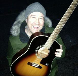 Music teacher Matt Torrence holding an acoustic guitar